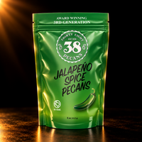 38 Pecans Jalapeño Spiced Pecans in the green 4 oz resealable pouch, photographed against a black background with warm gold lighting.